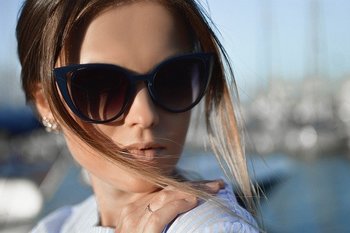 A young woman wearing sunglasses looks away from the camera
